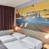 B&B Hotel Saarbrücken-Hbf guest room with twin beds, window, and cityscape mural in Saarbrücken