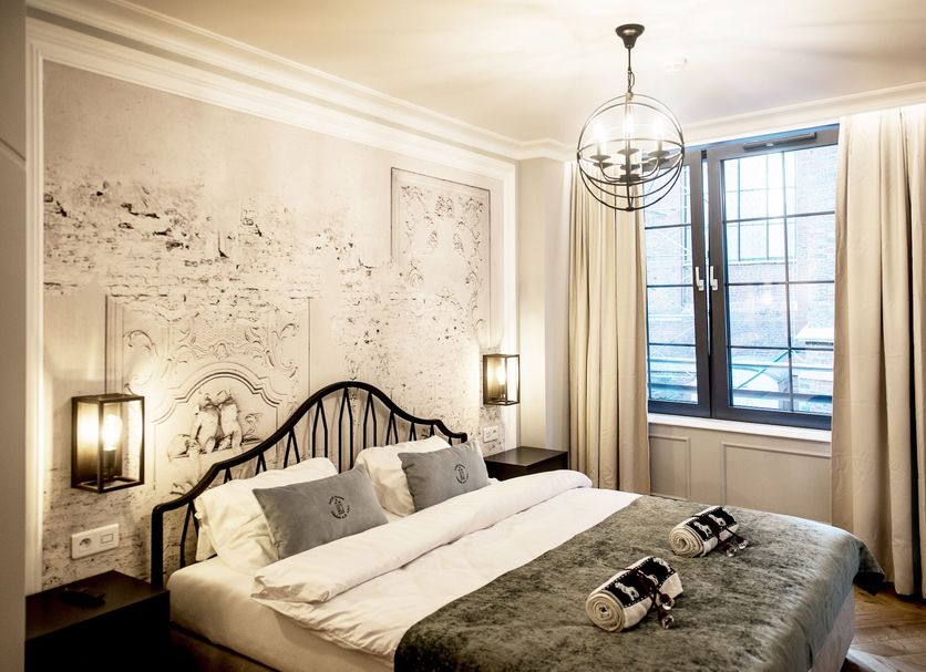 Gotyk House, Gdansk: elegant guest room with wrought-iron bed, ornate wall art, and tall window