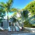 Seahorse Cottages on Sanibel - Adults Only with tropical palms and Adirondack chairs outside a cottage