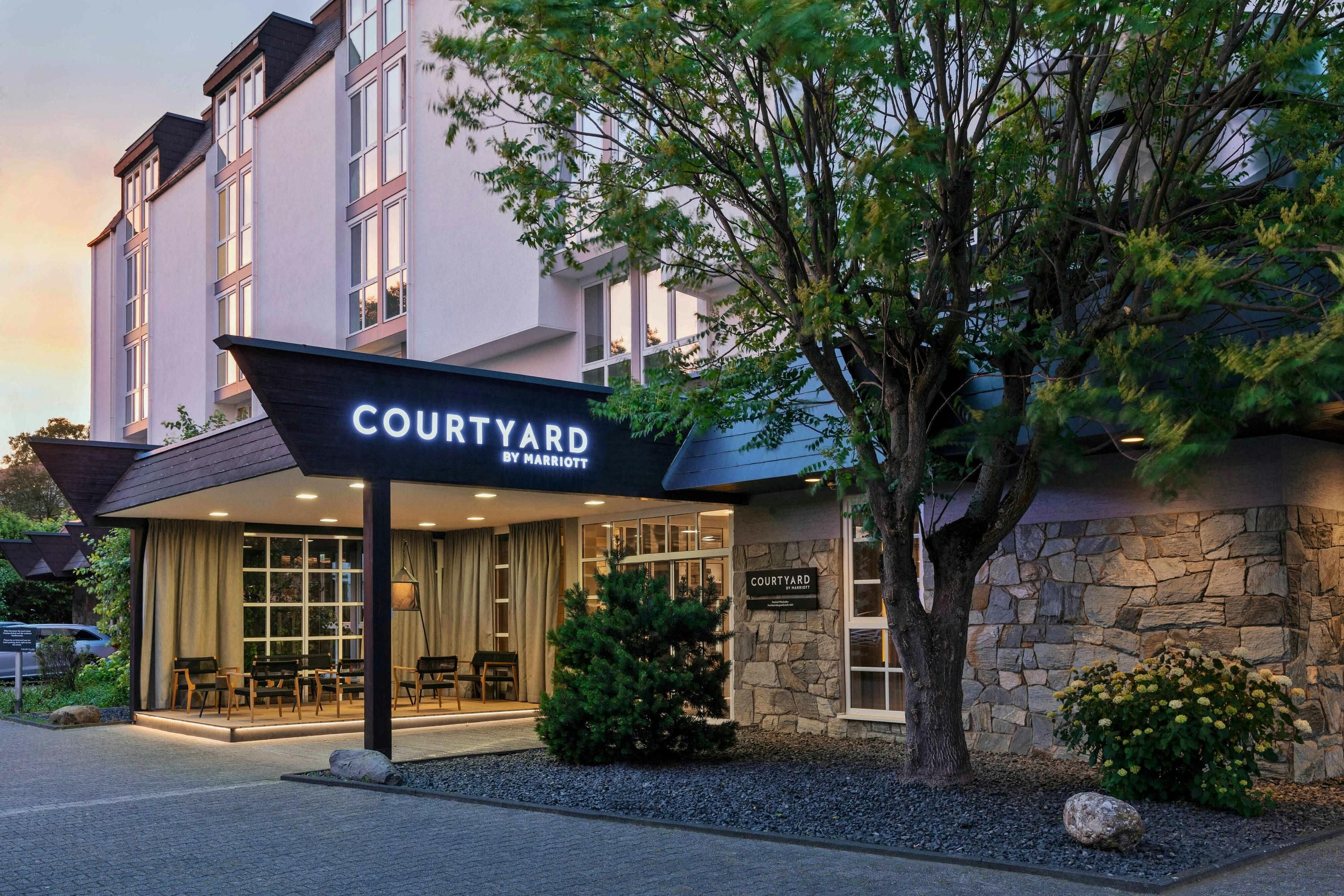 Courtyard by Marriott Wiesbaden-Nordenstadt exterior entrance with tree and stone facade in Wiesbaden