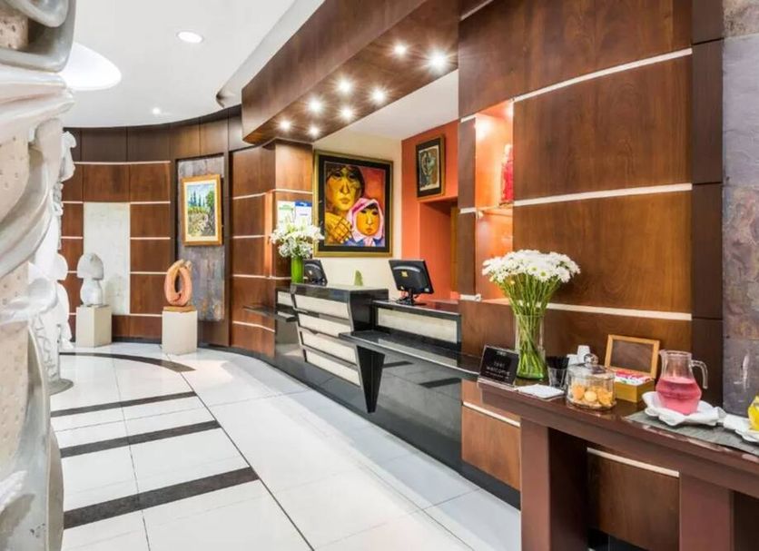 GH Galeria in Guayaquil lobby reception with wood paneling, black front desk, and floral arrangements