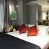 Triviho Hotel Rome guest room with king bed, colorful pillows, curtains, and bathroom doorway