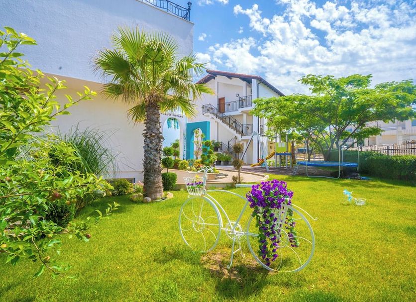 Royal Calisto Hotel in Sozopol with a landscaped garden, white bicycle planter, and palm tree