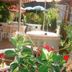 Auberge Aux Portes de Conques in Cransac: shaded outdoor patio with tables, chairs, and flowering plants