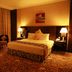 Sharjah Palace Hotel in Sharjah guest room with king bed, armchairs, lamps, and patterned carpet