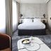 Hotel Les Bains Paris guest room with a neatly made bed, marble side table, and tall curtains in Paris
