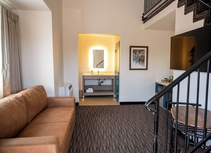 Lemon Heights Inn in Tustin hotel room with sofa, spiral staircase, and lit vanity area