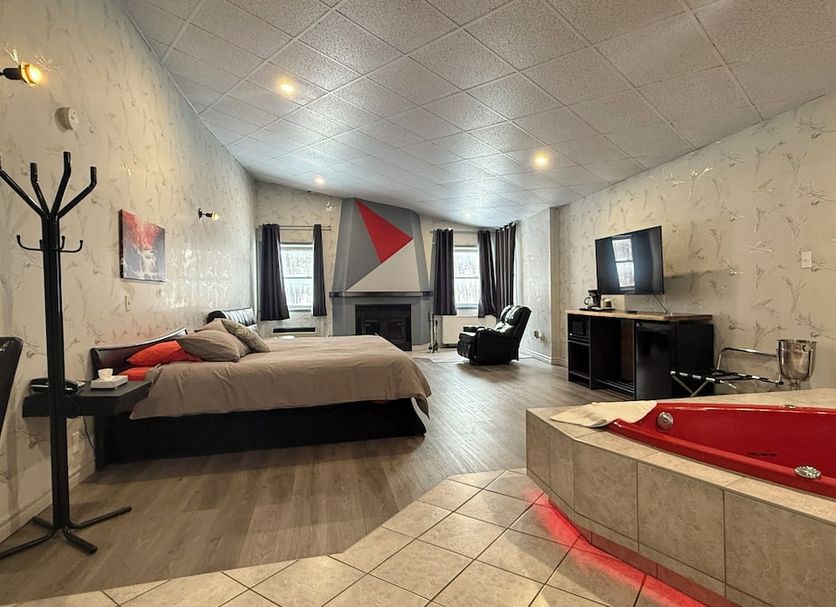 Hotel Motel La Marquise in Sherbrooke room with bed, TV, lounge chair and red corner bathtub