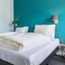 Villahotel Vlissingen guest room with twin beds, teal accent wall, and ensuite bathroom in Vlissingen