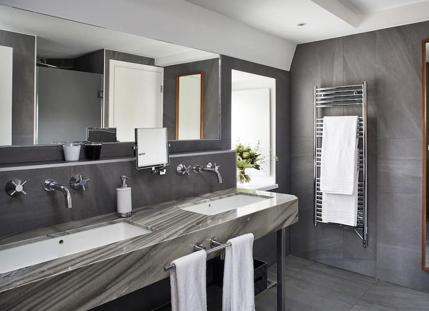 Pavillon Régent Petite France bathroom with double sinks, towel warmer, and mirror in Strasbourg