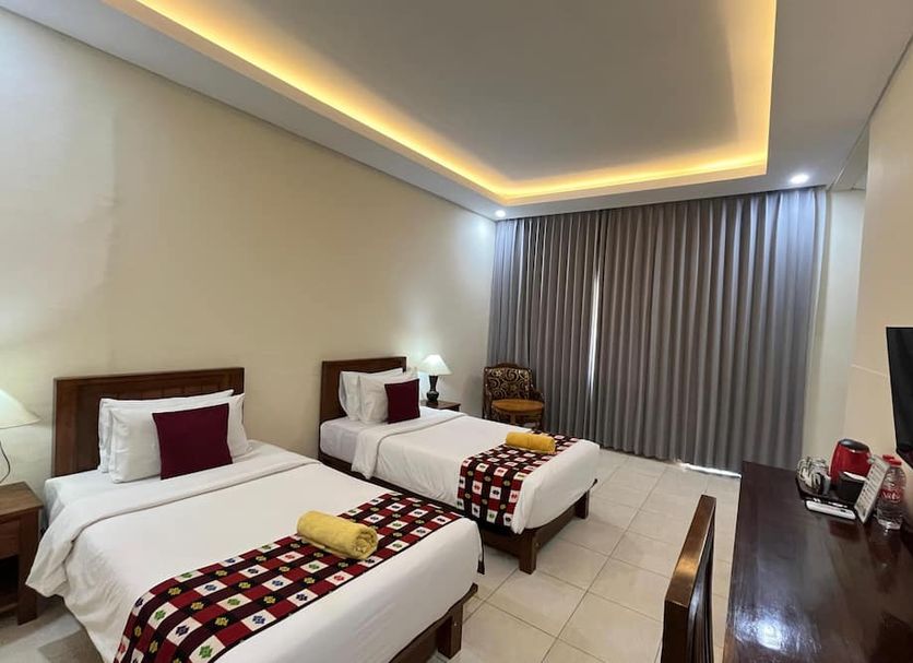 Lovina Beach Hotel in Buleleng guest room with two twin beds, curtains, and TV