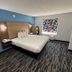 Jacksonville Inn & Suites guest room with king bed, blue accent wall, desk, and patterned carpet in Jacksonville