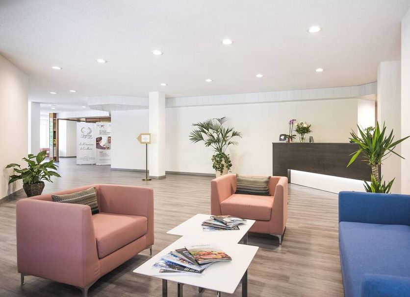 Centro Cadro Panoramica lobby lounge in Lugano with pink and blue chairs, plants, and coffee table