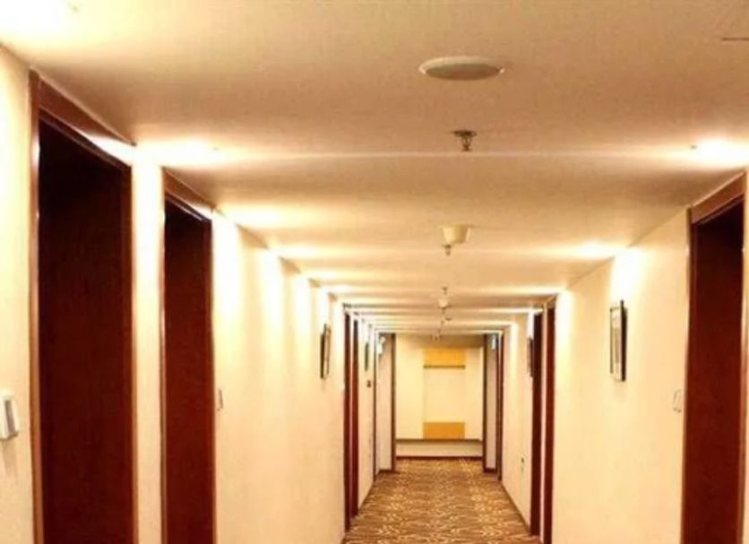 Haowei Mansion in Beijing hallway with patterned carpet and doors along a long interior corridor.