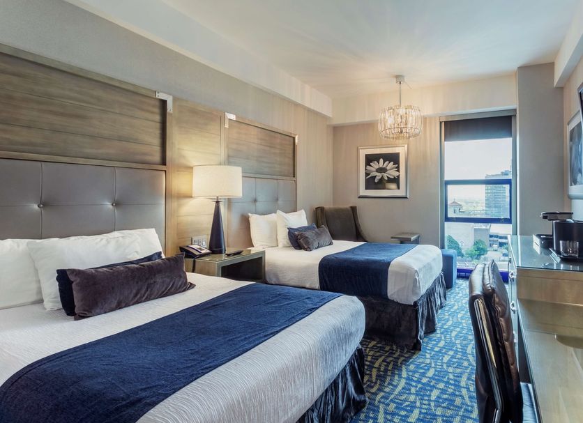 Robert Treat Hotel Newark guest room with two beds, desk, and city view from a window
