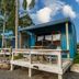 Tasman Holiday Parks - Coromandel cabin with deck chairs, palm trees, and mountain views