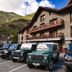 Hostal la Font in Os de Civís, stone alpine hotel with parked SUVs and mountain backdrop