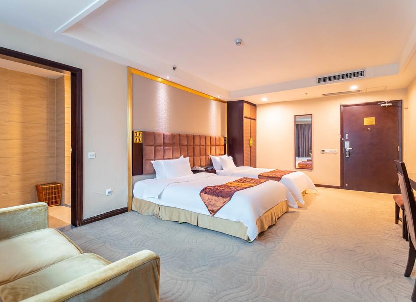 Fortune Hotel Guangzhou guest room with two beds, armchair, and entry door