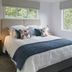 Treghan Luxury Lodge in Kerikeri bedroom with king bed, blue throw, and two windows