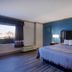 Motel 6 Burlington NC guest room with king bed, blue accent wall, bedside lamps, and city view