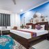 Hotel Taj Heritage in Agra guest room with king bed, colorful bedding, wall art of the Taj Mahal, and seating area