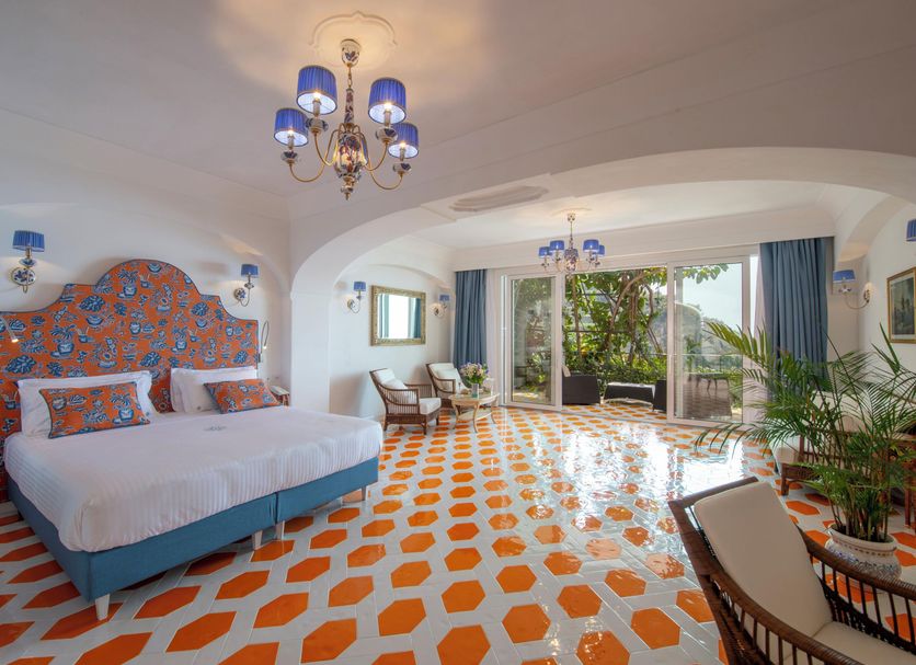 Hotel Pellegrino in Praiano: bright room with orange-patterned tile floor, blue accents, and sea-facing terrace