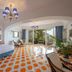 Hotel Pellegrino in Praiano: bright room with orange-patterned tile floor, blue accents, and sea-facing terrace