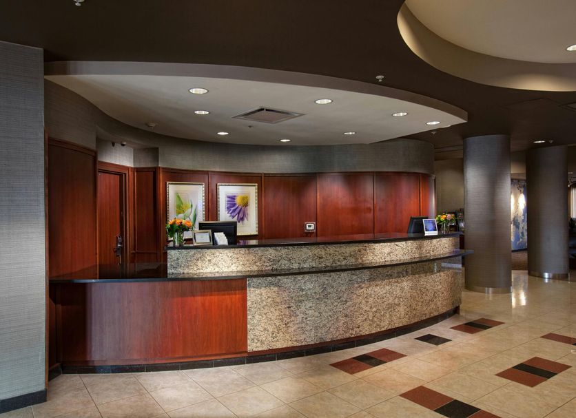 Courtyard by Marriott Fayetteville lobby front desk with wood paneling and curved stone reception counter