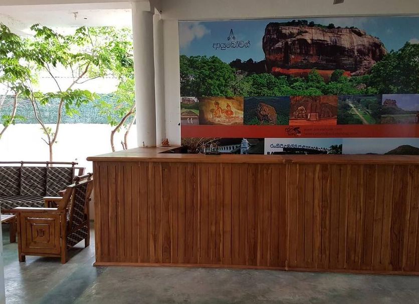Alikele Hotel Sigiriya lobby with wooden reception desk and mural wall in Dambulla