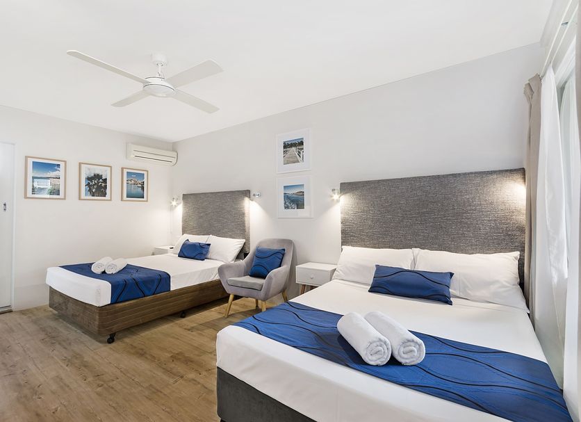 Beach House Motel in Townsville: bright twin room with two beds, ceiling fan and framed wall art