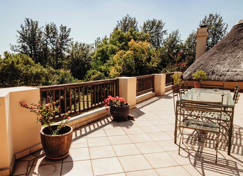 Blue Hills Lodge in Johannesburg terrace with potted flowers, patio table and chairs, and treetop views