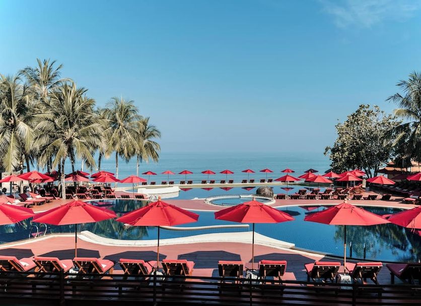 Khaolak Laguna Resort in Khao Lak with red umbrellas around a pool overlooking the ocean