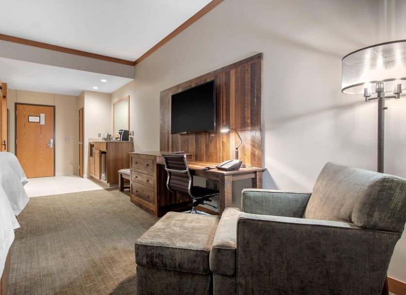Norfolk Lodge & Suites, Norfolk hotel room with desk, TV, armchair and entryway
