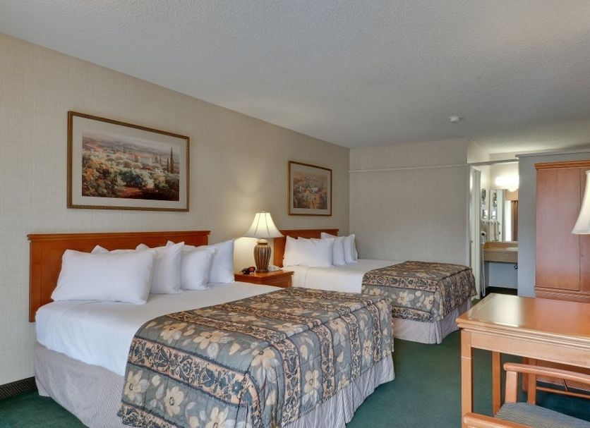 Vagabond Inn Ventura guest room with two double beds, lamps, desk and wardrobe in Ventura