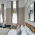 Victory House London guest room with curved window seat, tall windows and upholstered bed in London