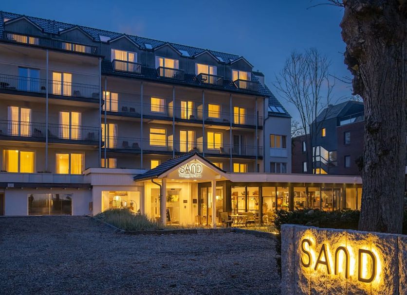 Sandnature hotel exterior at dusk in Timmendorfer Strand, with lit balconies and entrance