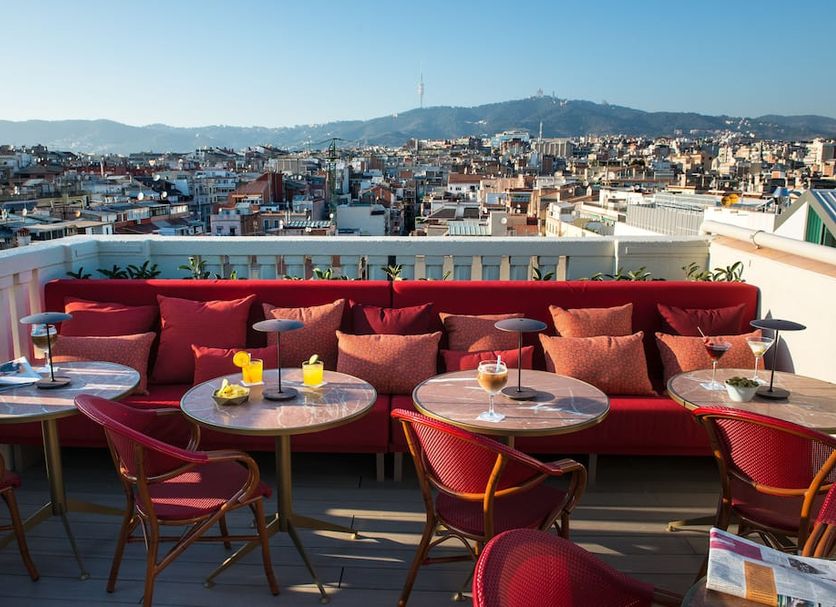 Vincci Mae Barcelona rooftop terrace with red seating and city and mountain views
