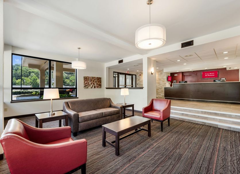 Lobby seating area at Red Roof Inn Birmingham South in Birmingham with red chairs, sofa, and front desk