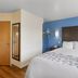 SureStay Plus by Best Western Niagara Falls East guest room with queen bed, blue accent wall and window curtains.