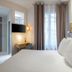 Makom Pereire in Paris guest room with bed, wall-mounted TV, desk, and bathroom entrance