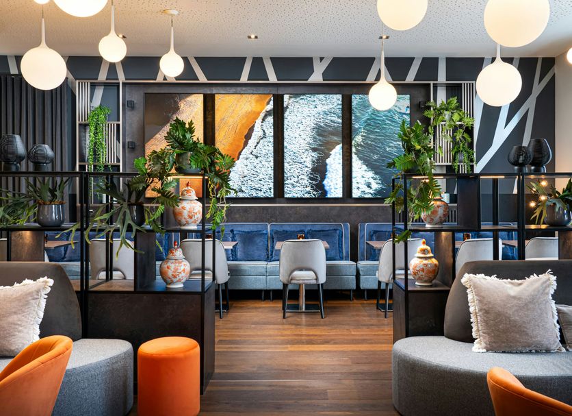 Leonardo Hotel Vienna Hauptbahnhof lounge with hanging globe lights, blue sofa, and abstract wall art in Vienna