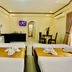 The Q Hotel Tagaytay guest room with two beds, dining table, TV, and arched doorway