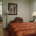 Arrowhead Mountain Inn guest room with king bed, armchair, lamps and framed wall art in Lake Arrowhead