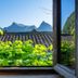 Yangshuo Secret Garden in Guilin, view of mountains framed by an open window above tiled roofs and greenery