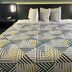 Studio 6 Huntsville. Al University Drive room with king bed, geometric patterned bedding, and bedside lamps