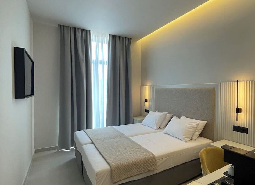 Palladion Boutique Hotel in Árgos bedroom with king bed, tall window, and warm ceiling lighting