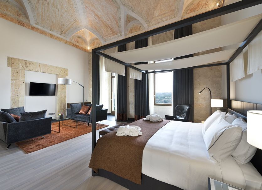 Áurea Convento Capuchinos in Segovia: elegant room with canopy bed, lounge seating and city view