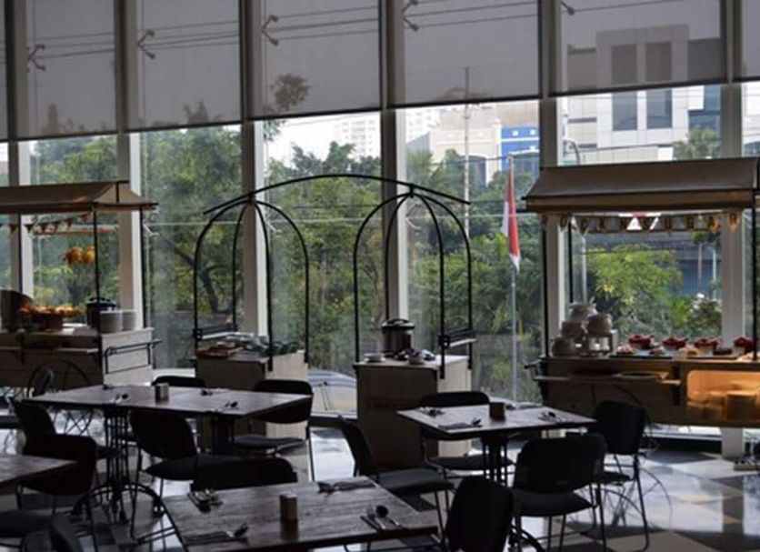 Luminor Hotel Jemursari by Wh lobby dining area with large windows and city view in Surabaya