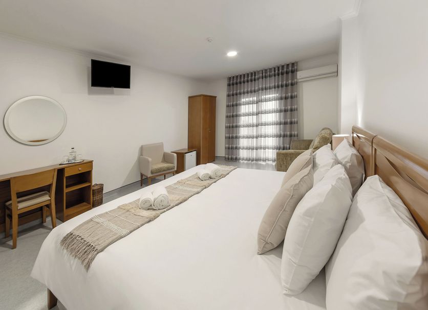 Wot Pinhalmar Soul in Peniche bedroom with double bed, desk, chair, wall TV and window curtains