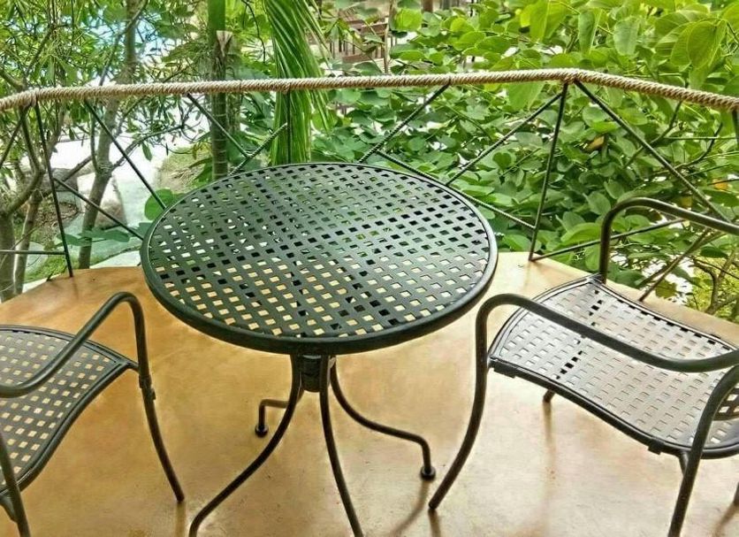 Amphawa Club Resort & Spa balcony with round metal table and two chairs among lush greenery in Amphawa